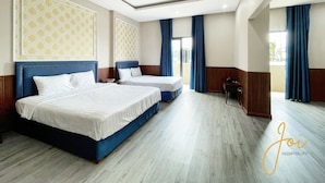 A hotel room with two beds, a wooden floor, and a view of the outdoors. - Phuong Hoang Hotel  (Ho Chi Minh City)
