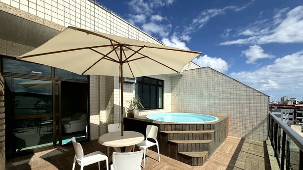 En tagterrasse med jacuzzi, udendørs møbler og udsigt over byen.