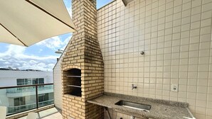 En balkon med en murstensovn, vask og haveslange.