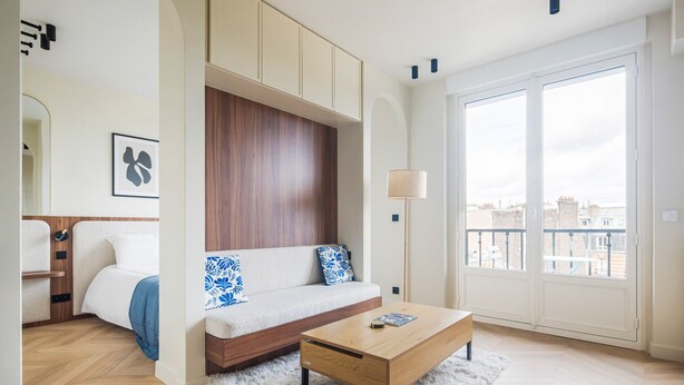 Een moderne woonkamer met een bank, een salontafel en uitzicht op de stad door grote ramen.