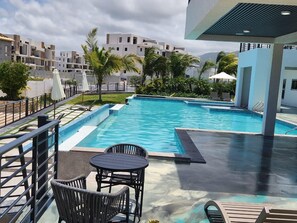 Una piscina con un deck circundante, sillas y sombrillas.