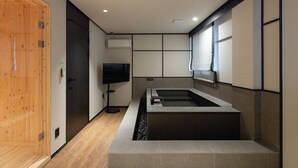 Un baño moderno con puerta de madera, bañera integrada y televisor.