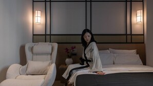 Una habitación de hotel moderna con una cama, una silla y dos luces fijadas a la pared.