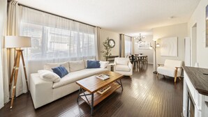 Un salon moderne comprenant un canapé, des fauteuils, une table basse et un coin repas.