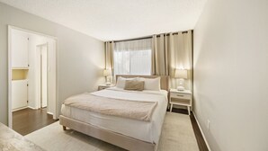 Une chambre à coucher avec un grand lit, des tables de chevet avec des lampes, une armoire et une fenêtre avec des rideaux.