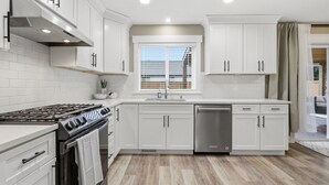 Une cuisine moderne avec des meubles blancs, une cuisinière en acier inoxydable et un lave-vaisselle.