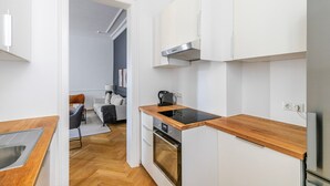 A modern kitchen with white cabinets, a wooden countertop, and a built-in oven. - Blueground | Josefstadt, washer/dryer, nr Votivkirche (Vienna)
