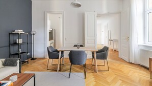 A modern living room with a dining table and chairs, a sofa, a bookshelf, and a floor lamp. - Blueground | Josefstadt, washer/dryer, nr Votivkirche (Vienna)