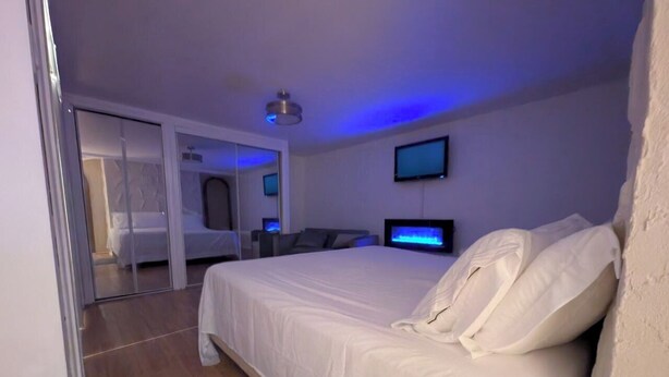 A modern hotel room with a large bed, a flat-screen TV, and a ceiling fan. - Home rental S7 (Bois-des-Filion)