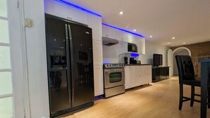A modern kitchen with stainless steel appliances, white cabinets, and blue LED lighting. - Home rental S7 (Bois-des-Filion)