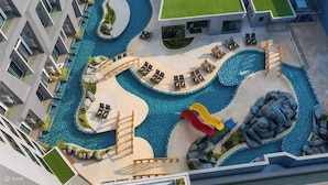 A modern hotel with a central swimming pool, sun loungers, and a children's slide. - Utopia Loft Aparthotel by Sabai Sands (Rawai)
