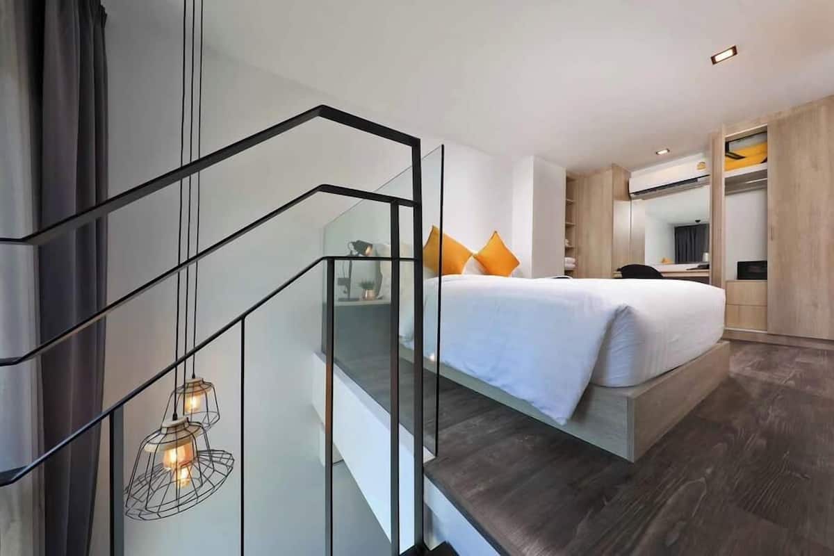 Moderni hotellihuone, jossa on sänky, työpöytä ja vaatekaappi.