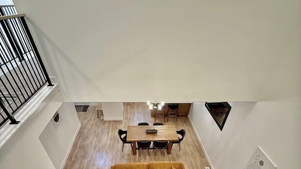 Un'ampia zona giorno con pavimento in legno, un divano, un tavolo da pranzo con sedie e una scala.