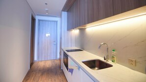 A modern kitchen with a built-in oven, a stainless steel sink, and wooden cabinets. - OceanView Hạ Long • Large Balcony • TwinBed (Thành phố Hạ Long)