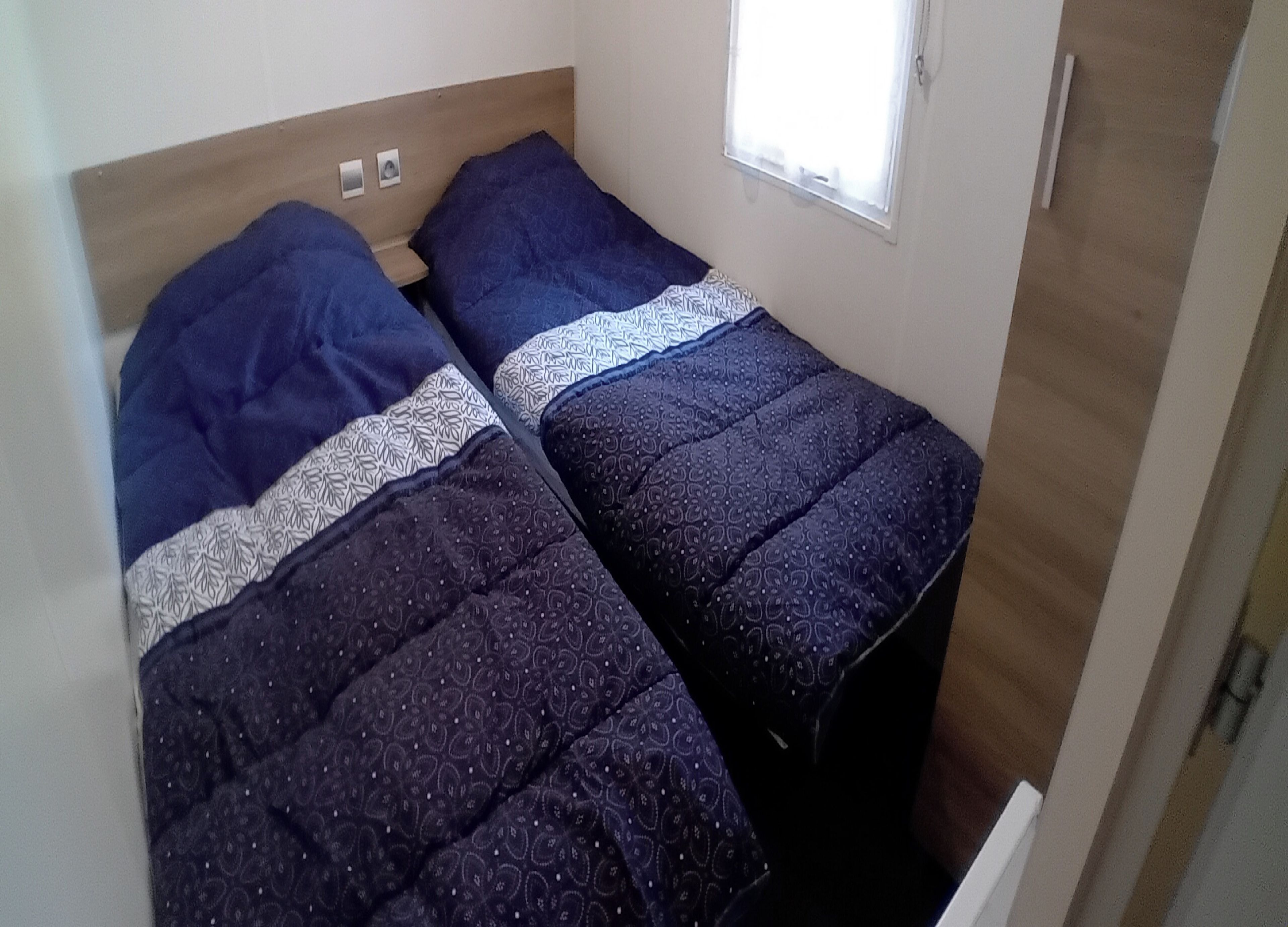 Una habitación pequeña con dos camas, cada una con colcha y almohadas estampadas.