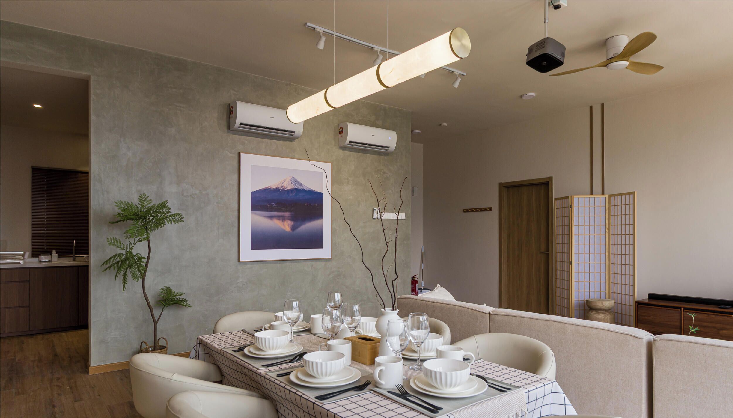 A dining area with a table set for four, air conditioning units, a framed picture on the wall, and a ceiling fan.