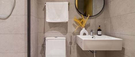 Een moderne badkamer met toilet, wastafel en spiegel.