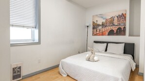 Una camera da letto con un letto, una finestra con persiane, un termosifone e un quadro raffigurante un ponte.