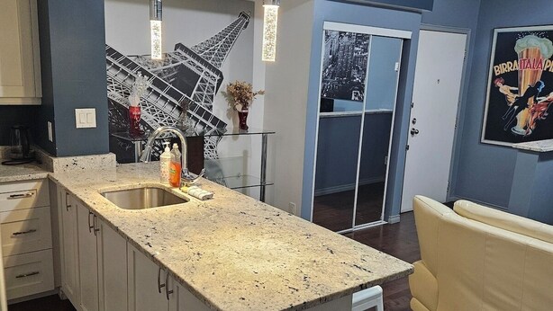 Een moderne keuken met een groot kookeiland, witte kastjes en een donkere houten vloer.