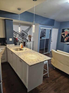Une cuisine moderne dotée d’un grand îlot central, de meubles blancs et d’un plancher en bois foncé.