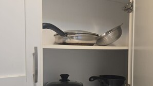 Una cocina con armarios blancos, un tostador, una tetera y una cafetera sobre la encimera.