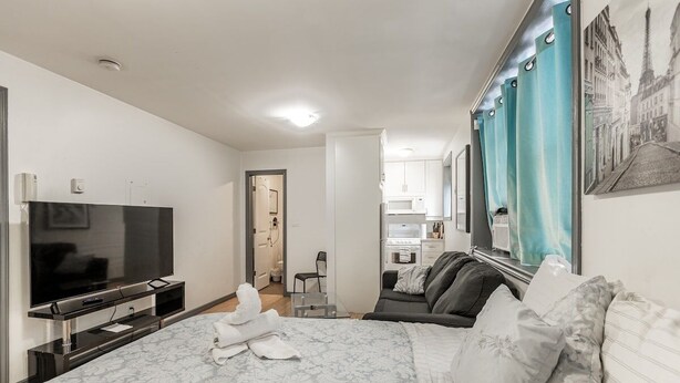 Habitación de hotel con cama, televisor, baño y kitchenette.