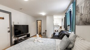 Habitación de hotel compacta con cama, televisor, kitchenette y baño.