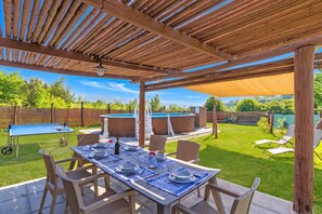 An outdoor patio with a table set for dining, surrounded by chairs, and a pool area in the background. - Family Home Margherita Pool Mugello 6, Vicchio, Italy (Vicchio)