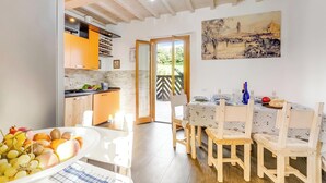 Cozinha luminosa com armários de madeira e área de jantar com mesa posta para dois.