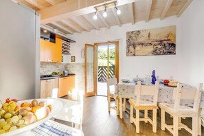 A bright kitchen with wooden cabinets and a dining area with a table set for two. - Family Home Margherita Pool Mugello 6, Vicchio, Italy (Vicchio)