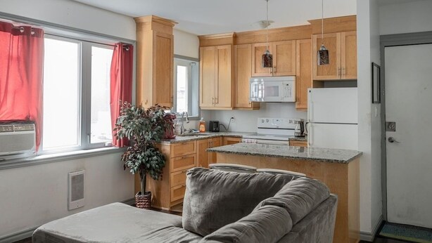 A compact kitchen with wooden cabinets, a white refrigerator, and a granite countertop. - Lovely App Downtown Ottawa 211D (Ottawa)