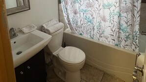 Een badkamer met wastafel, toilet en bad.