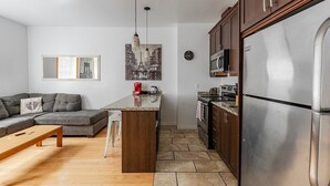 Eine moderne Küche mit einer zentralen Kochinsel, Edelstahlgeräten und einem Essbereich mit Sofa und Couchtisch.