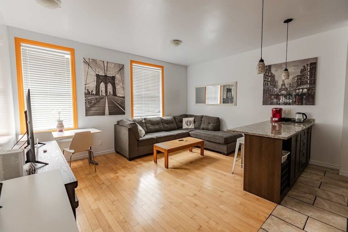Uma sala de estar moderna com sofá, mesa de centro e ilha de cozinha.
