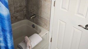 Ein Badezimmer mit einer Badewanne, einer Dusche und einer weißen Tür.