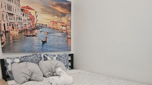 Ein Schlafzimmer mit Bett, Kissen, einem Nachttisch und einem großen Stadtbild an der Wand.