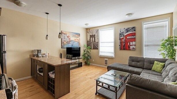 A modern living room with a sofa, coffee table, and kitchen area with a TV and counter. - 2-Bed App Downtown Ottawa 36D (Ottawa)