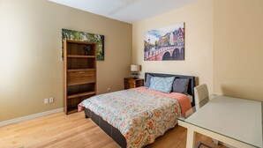 A bedroom with a bed, a desk, a bookshelf, and a painting on the wall. - 2-Bed App Downtown Ottawa 36D (Ottawa)