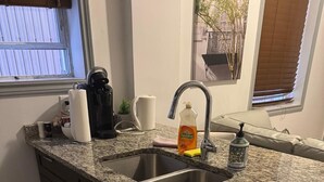 Een keuken met een granieten aanrecht, een roestvrijstalen spoelbak en een lade-organizer met keukengerei.