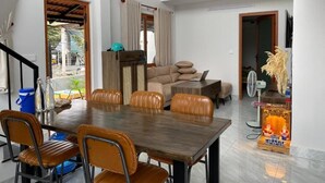 Ein großzügiger Wohnbereich mit Esstisch aus Holz und Ledersesseln, einer Couch und einem kleinen dekorativen Gegenstand auf einem Sockel.