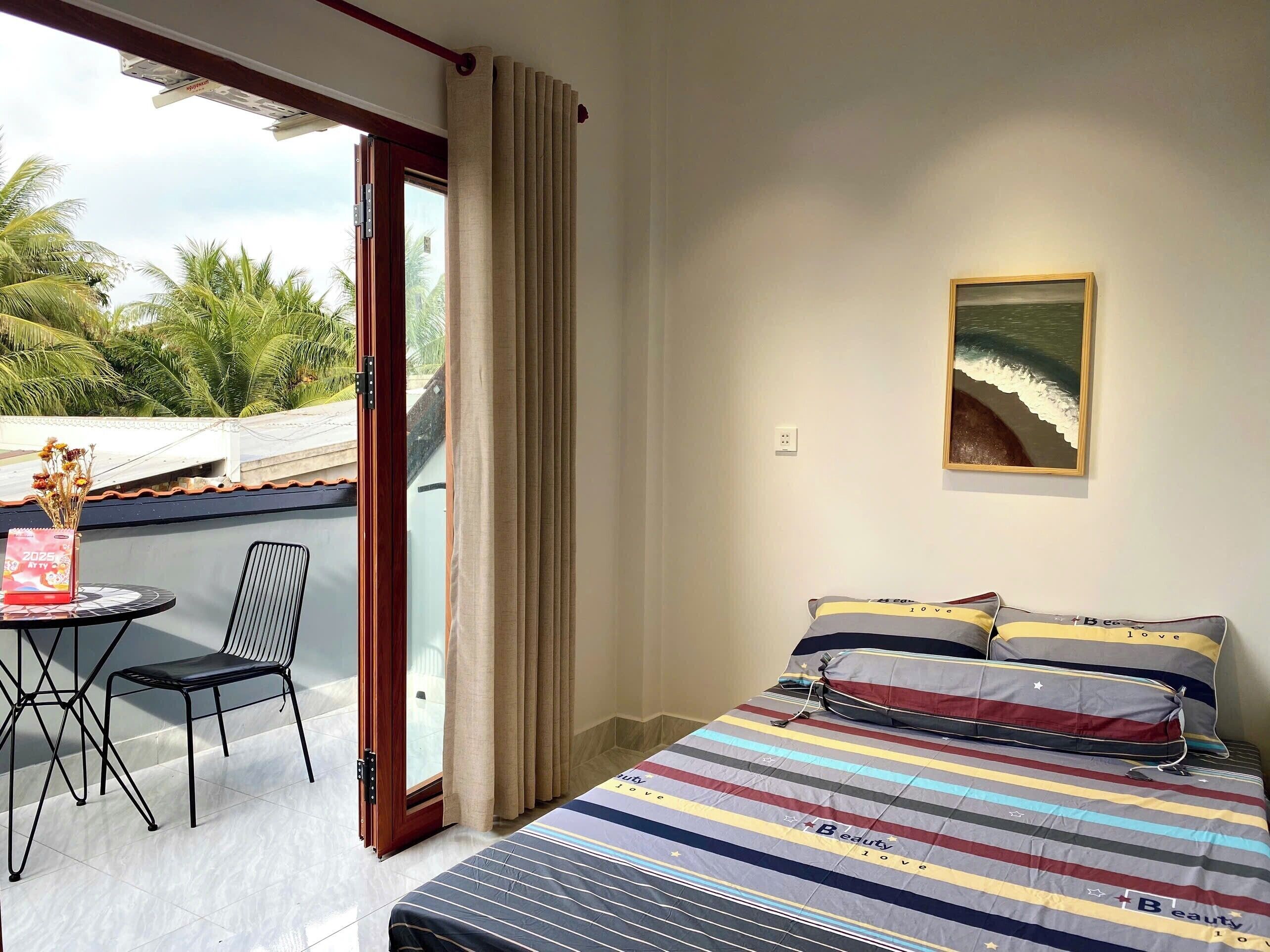 A bedroom with a bed, a chair, a table, and a painting on the wall.