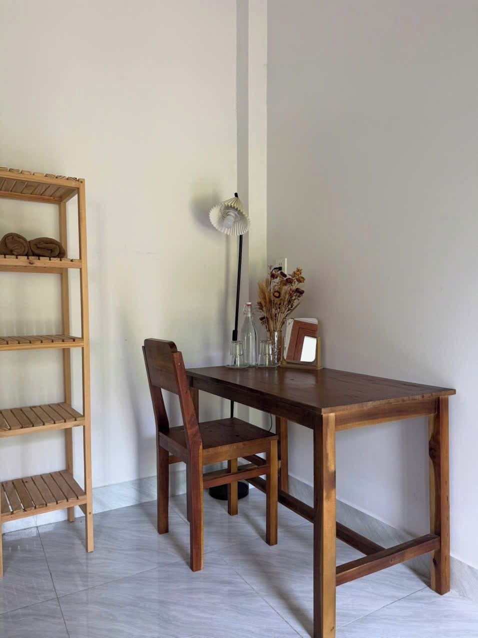 A wooden dining table with chairs, a wooden shelf unit, and a floor lamp.