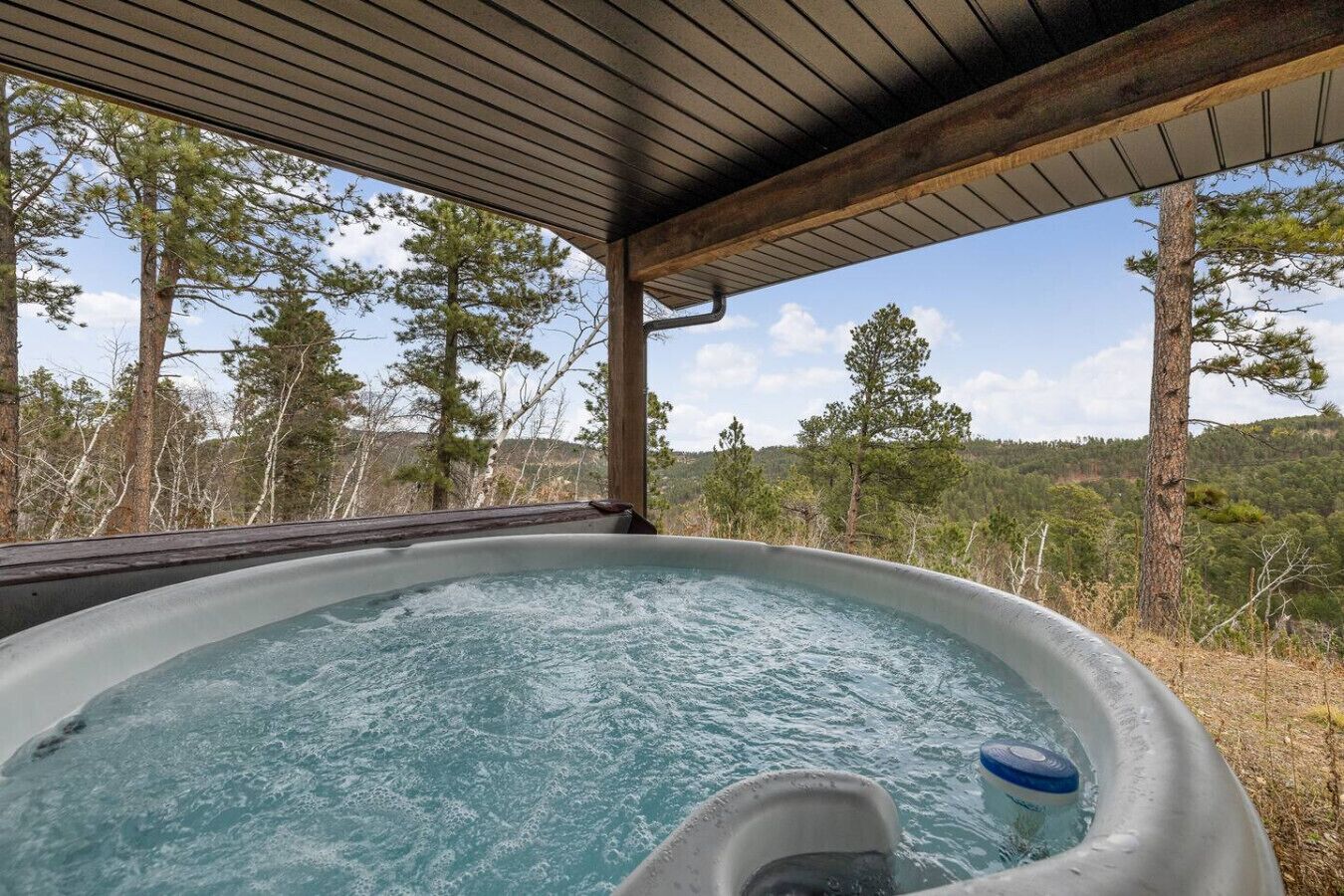 Indulge yourself in the steaming, covered hot tub with a glass roof overhead, offering a truly magnificent backdrop of the rolling forest hills