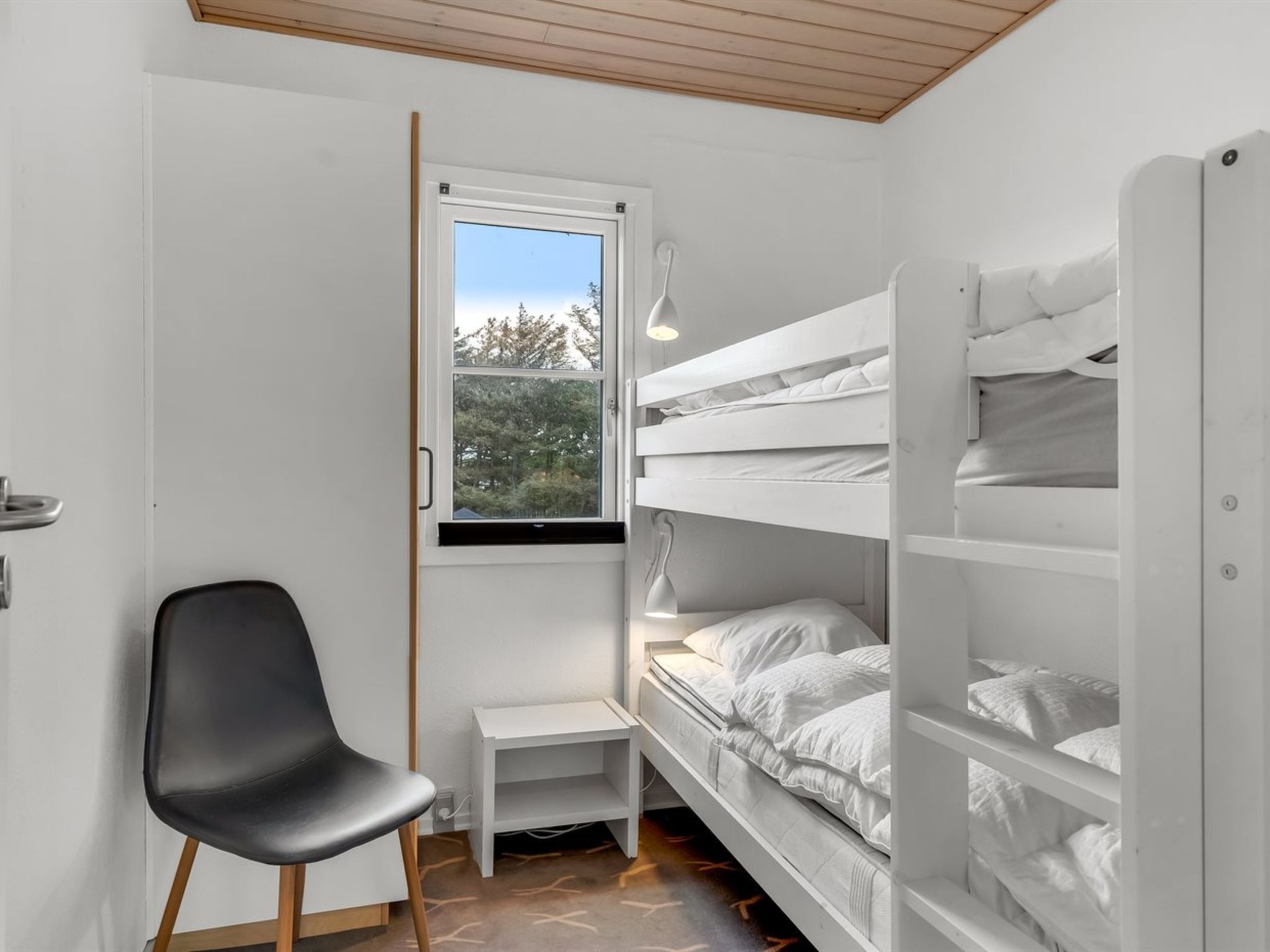 A compact room with bunk beds, a small desk, and a chair.