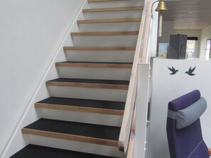 A staircase with wooden steps and black carpet, leading to a landing with a white cabinet and two bird decals. - "Epiphania" - 100m to the fjord by Interhome (Vestervig)