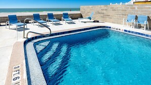 Ein Swimmingpool mit einer Tiefenmarkierung von 3 Fuß 6 Zoll, umgeben von Liegestühlen und Blick auf den Strand.