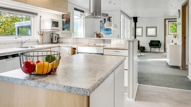 A modern kitchen with a central island, stainless steel appliances, and a large window providing natural light.