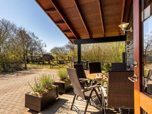 A covered outdoor seating area with wicker chairs and a table, surrounded by planters and a wooden deck. - "Jaane" - 250m to the fjord by Interhome (Vestervig)