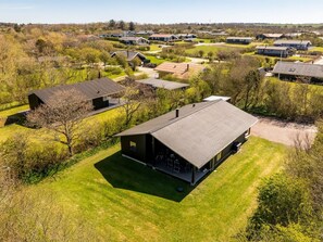 A modern house with a large deck, surrounded by a well-maintained lawn and other houses in a rural setting. - "Jaane" - 250m to the fjord by Interhome (Vestervig)
