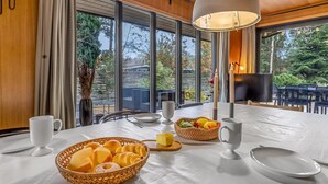 A dining area with a large table, white tableware, and a basket of bread and fruit. - "Sheyla" - 70m from the sea by Interhome (Væggerløse)